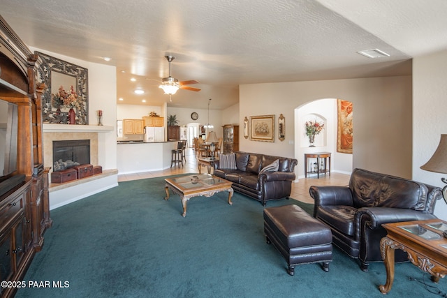 tiled living area with visible vents, lofted ceiling, arched walkways, ceiling fan, and a textured ceiling