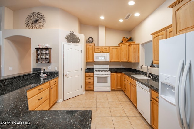 kitchen with visible vents, a sink, dark stone counters, white appliances, and light tile patterned floors