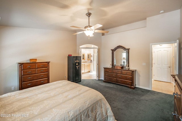 bedroom with ensuite bath, carpet flooring, baseboards, and a ceiling fan