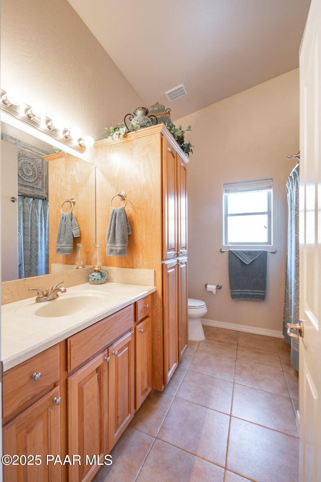 bathroom with vanity, visible vents, baseboards, tile patterned flooring, and toilet