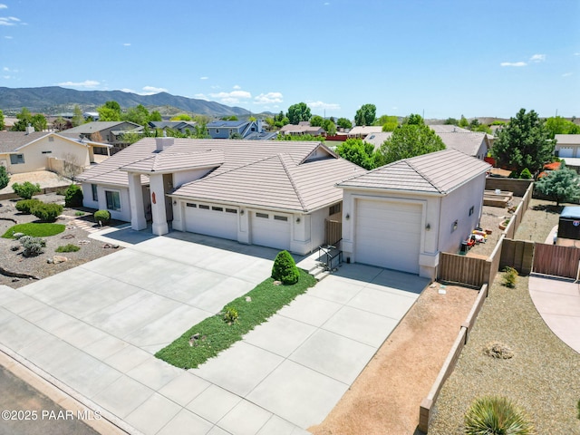 view of front of home with concrete driveway, a tiled roof, fence, and a garage