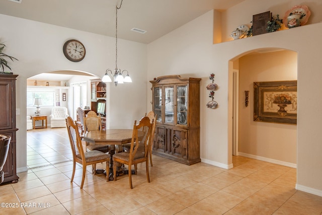 dining space with light tile patterned flooring, visible vents, arched walkways, and a towering ceiling