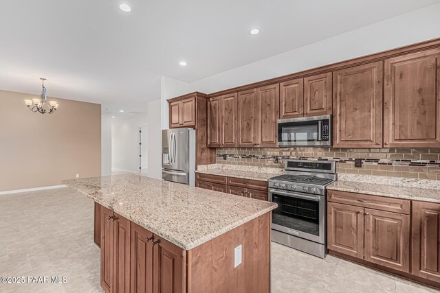 893 Canyon Breeze Ct, Prescott, AZ 86303 - kitchen featuring appliances with stainless steel finishes, tasteful backsplash, a chandelier, a kitchen island, and light stone counters