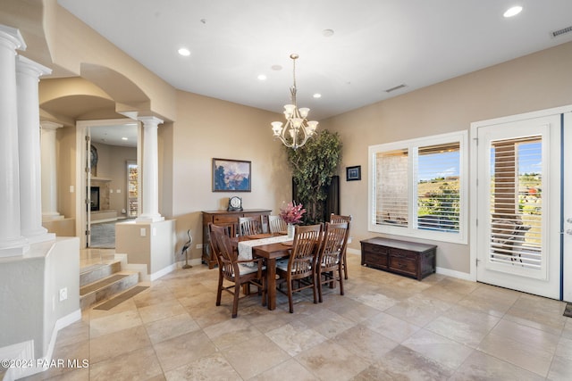 dining area featuring decorative columns and a notable chandelier