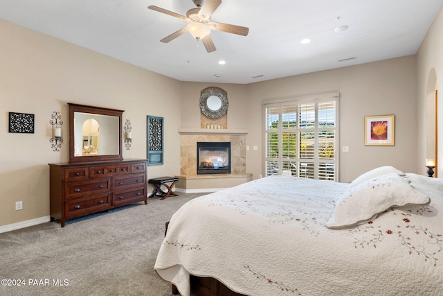 carpeted bedroom with a tile fireplace and ceiling fan