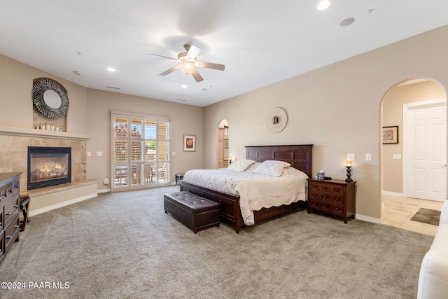 bedroom with access to exterior, ceiling fan, light colored carpet, and a tile fireplace