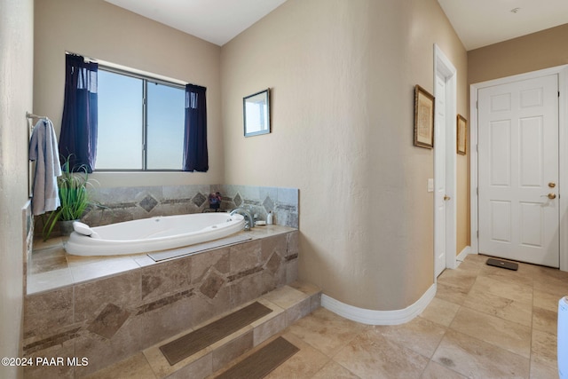 bathroom with tile patterned flooring and tiled bath