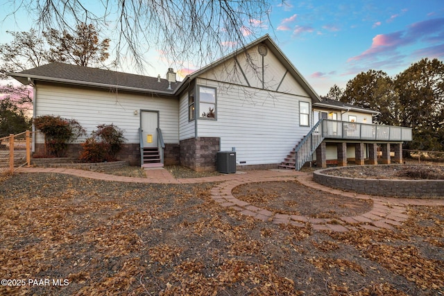 back house at dusk with a wooden deck and cooling unit