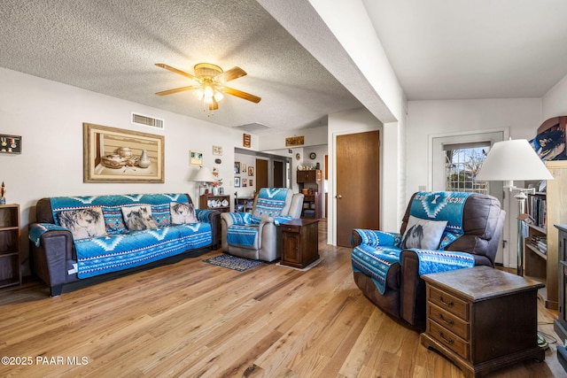 living room featuring ceiling fan, a textured ceiling, and light hardwood / wood-style flooring