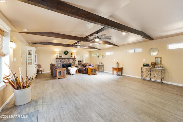 living room with vaulted ceiling with beams, ceiling fan, a stone fireplace, and hardwood / wood-style flooring