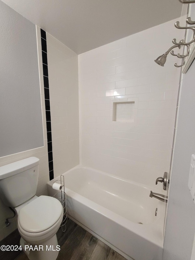 bathroom with hardwood / wood-style flooring, toilet, and tiled shower / bath