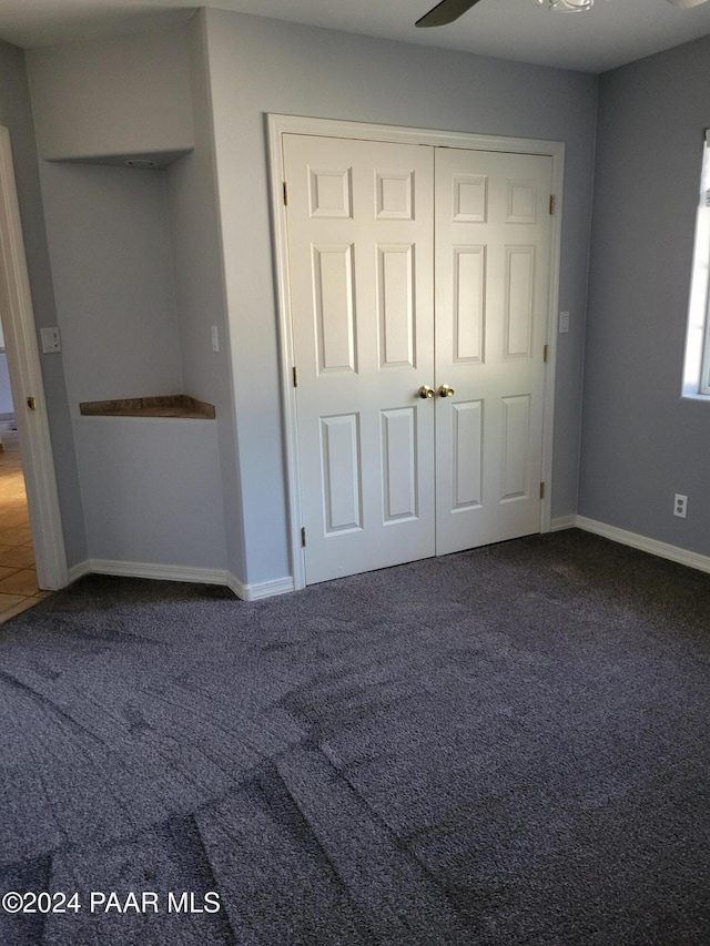 unfurnished bedroom with ceiling fan, a closet, and carpet