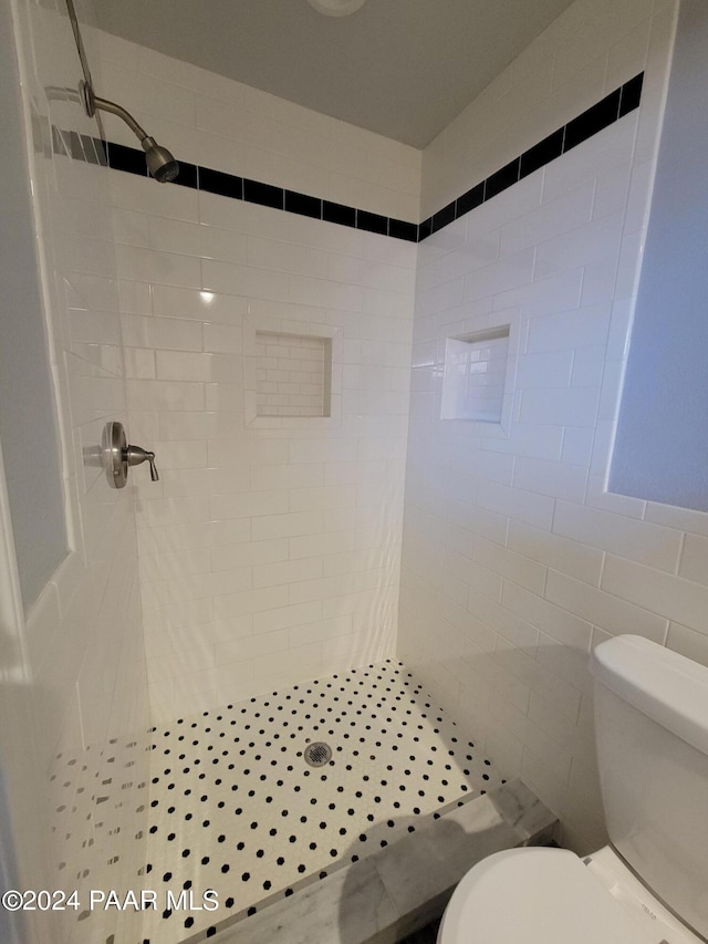 bathroom with toilet, tile walls, and tiled shower