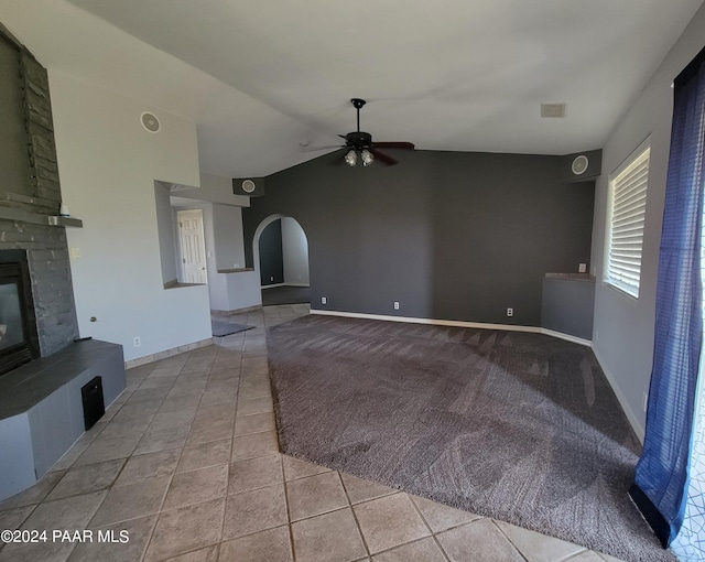 unfurnished living room with a large fireplace, ceiling fan, light tile patterned flooring, and vaulted ceiling