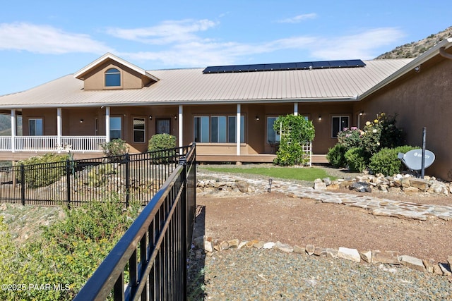 9520 Poland Rd, Mayer, AZ 86333 - rear view of house featuring solar panels, covered porch, stucco siding, metal roof, and fence