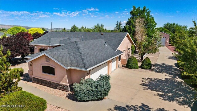 977 Kristin St, Chino Valley, AZ 86323 - view of front of home with stucco siding, an attached garage, roof with shingles, stone siding, and concrete driveway