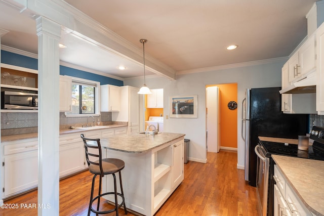 kitchen with tasteful backsplash, under cabinet range hood, light countertops, appliances with stainless steel finishes, and a sink