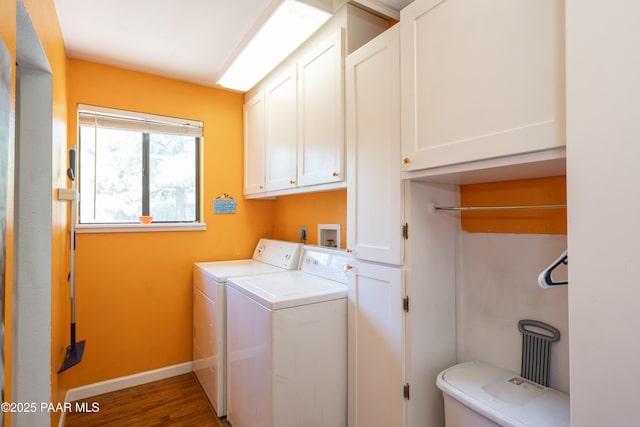 clothes washing area with washer and clothes dryer, cabinet space, baseboards, and wood finished floors