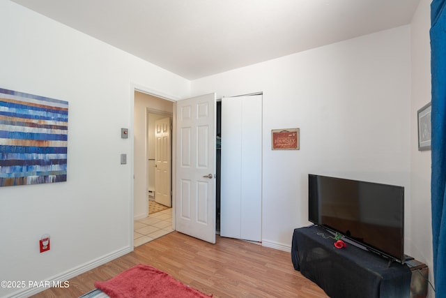 bedroom with a closet, baseboards, and light wood finished floors