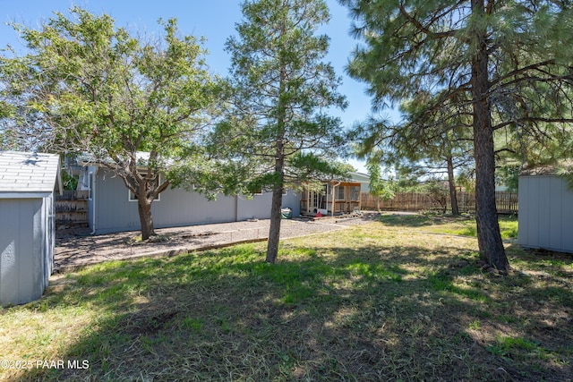 view of yard with a storage shed, a fenced backyard, and an outdoor structure