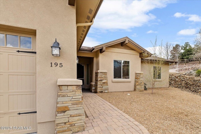 entrance to property featuring stone siding and stucco siding