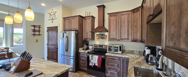 kitchen featuring hanging light fixtures, stainless steel appliances, light stone countertops, and wall chimney exhaust hood