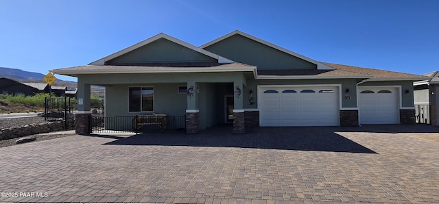 view of front facade with stucco siding, covered porch, decorative driveway, stone siding, and an attached garage