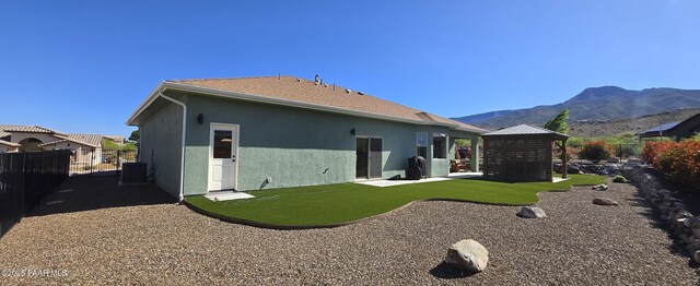 rear view of house featuring stucco siding, a gazebo, fence, a mountain view, and cooling unit