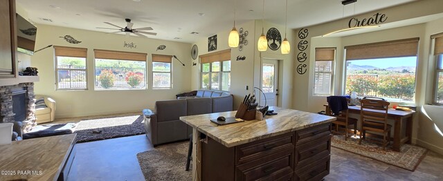 office space with baseboards, ceiling fan, and a stone fireplace