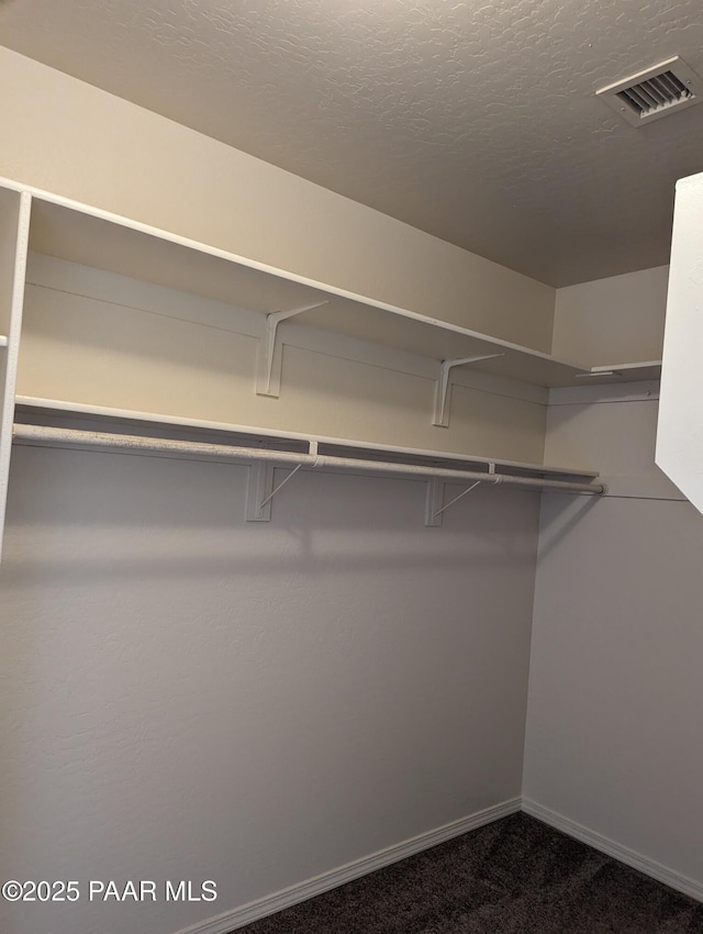 walk in closet featuring visible vents and dark carpet