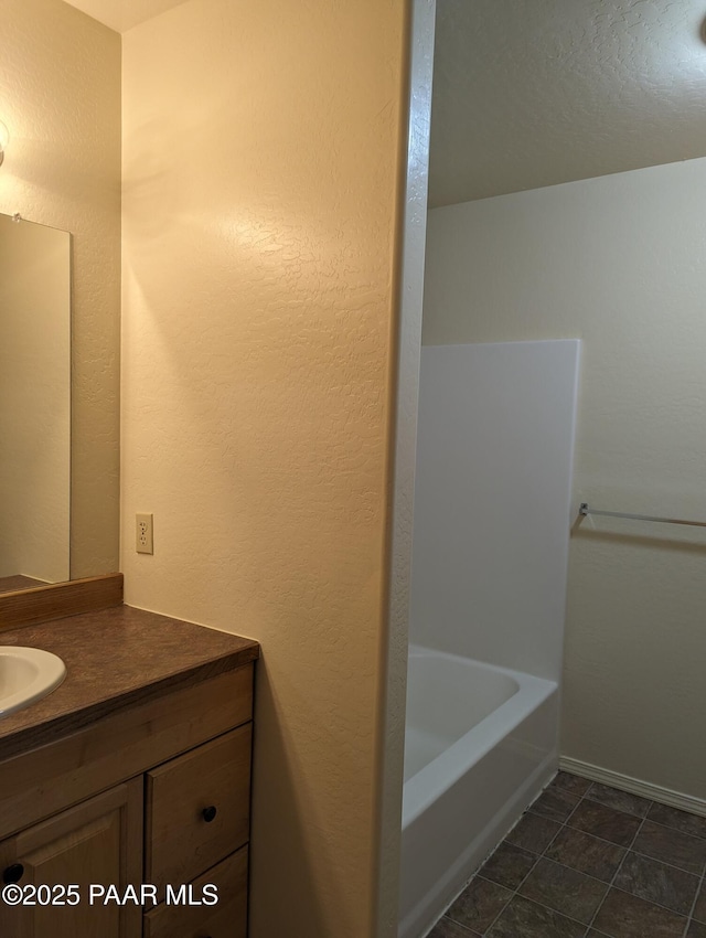 bathroom featuring a textured wall, a washtub, and vanity