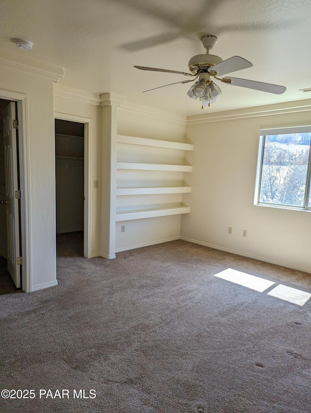 unfurnished bedroom featuring visible vents, ornamental molding, a ceiling fan, carpet flooring, and baseboards