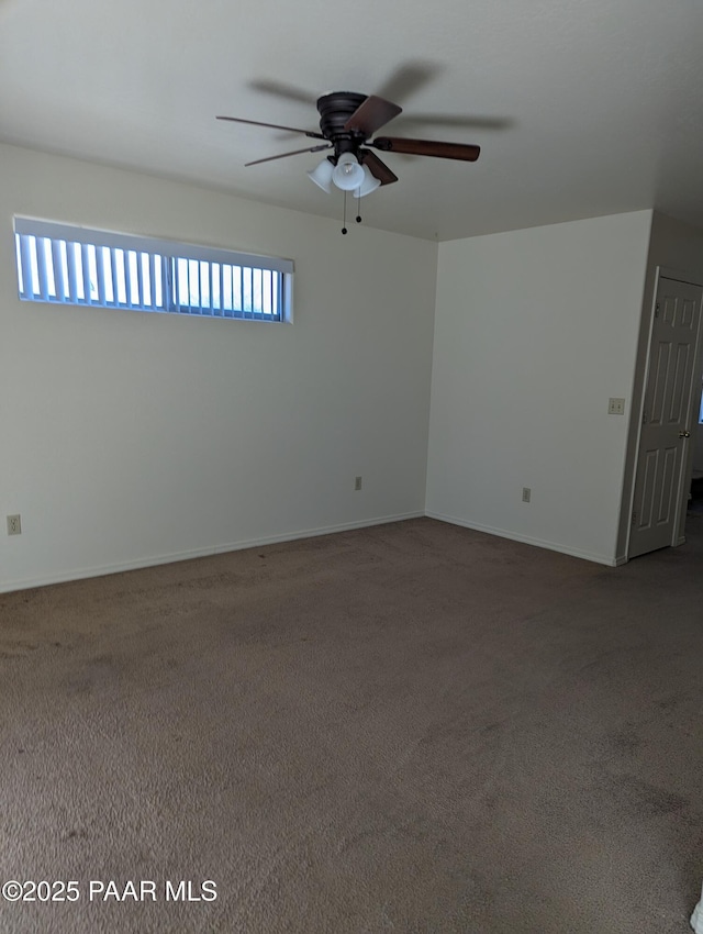 carpeted spare room with a ceiling fan and baseboards