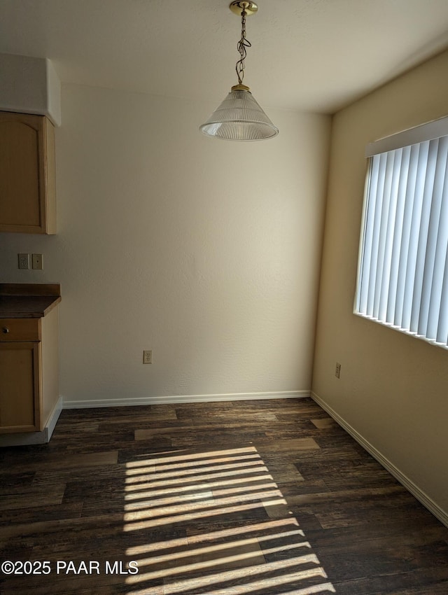 unfurnished dining area with dark wood-style floors and baseboards