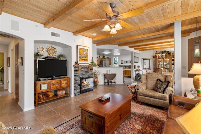 living area featuring dark tile patterned floors, ceiling fan, visible vents, arched walkways, and wooden ceiling