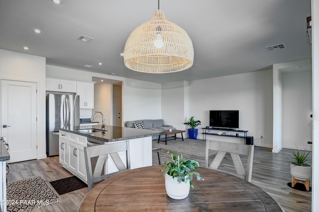 dining room with light wood-type flooring, a notable chandelier, and sink