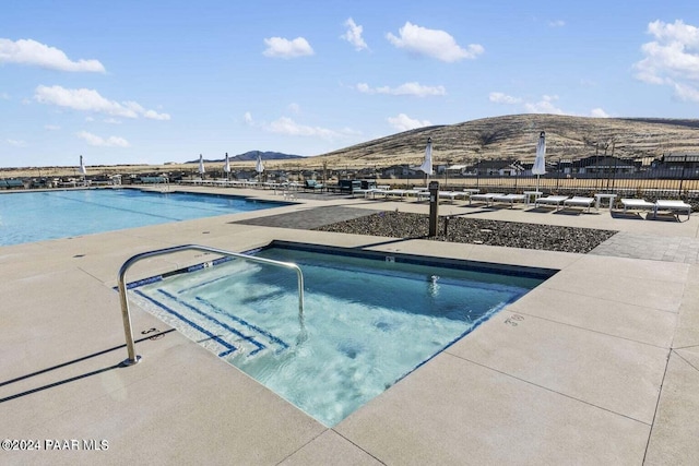 view of swimming pool with a mountain view, a community hot tub, and a patio area