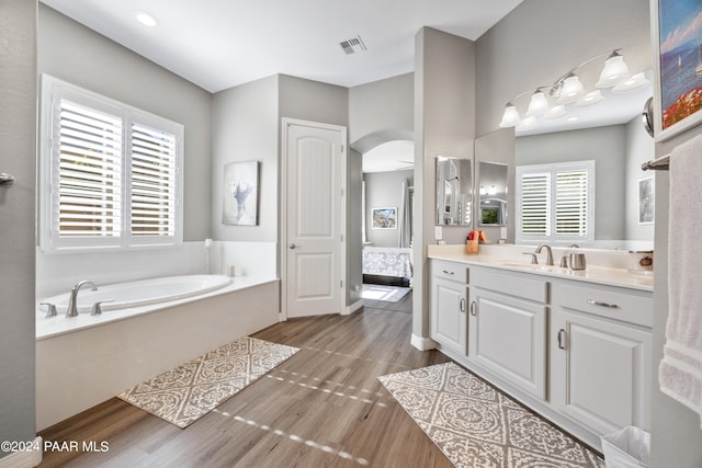 bathroom with a washtub, wood-type flooring, and vanity