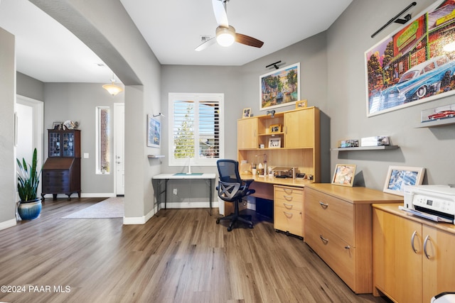 home office with ceiling fan, light hardwood / wood-style flooring, and built in desk