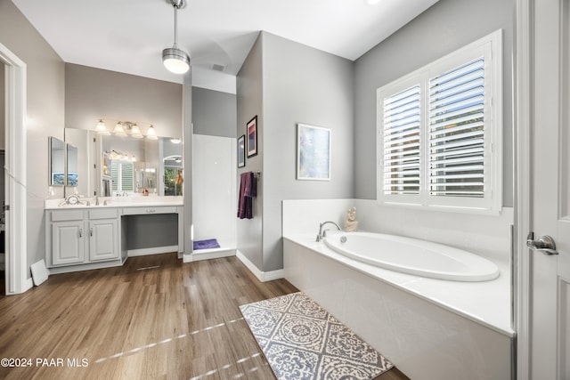 bathroom with vanity, a bath, and wood-type flooring