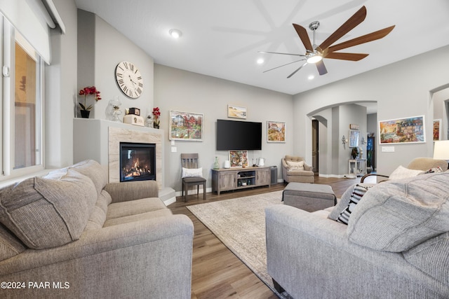 living room featuring ceiling fan, light hardwood / wood-style floors, and a premium fireplace