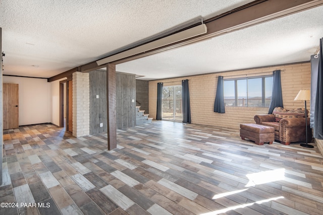 basement with wood-type flooring, a textured ceiling, and brick wall