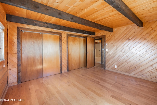 unfurnished bedroom featuring wood walls and beamed ceiling