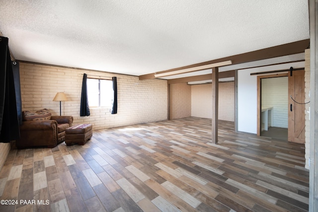 basement with hardwood / wood-style flooring, a barn door, and a textured ceiling