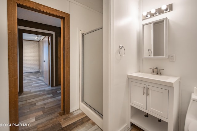 bathroom with hardwood / wood-style floors, vanity, toilet, and a shower with door