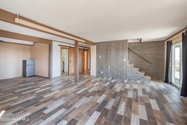 interior space featuring a barn door, wood walls, dark wood-type flooring, and a textured ceiling