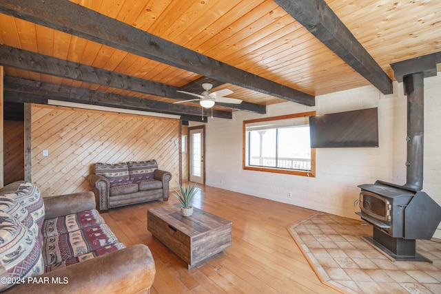 living room with a wood stove, light hardwood / wood-style flooring, beamed ceiling, and wood ceiling