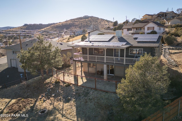 rear view of property featuring central air condition unit, a mountain view, and solar panels