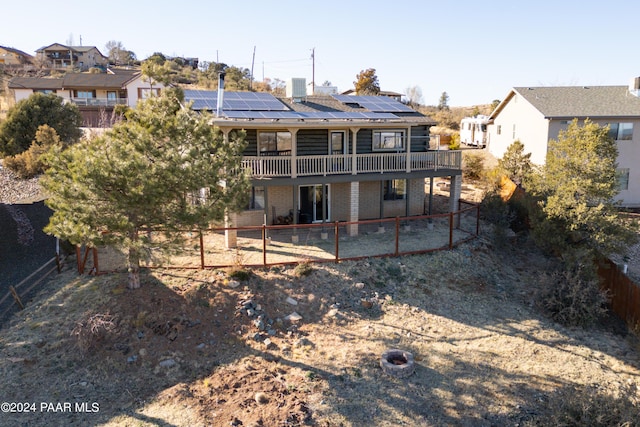 back of property with a deck and solar panels