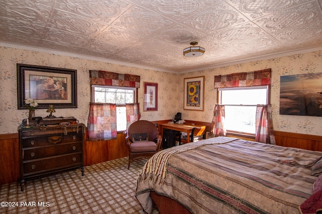 bedroom featuring a wainscoted wall, ornamental molding, an ornate ceiling, and wallpapered walls